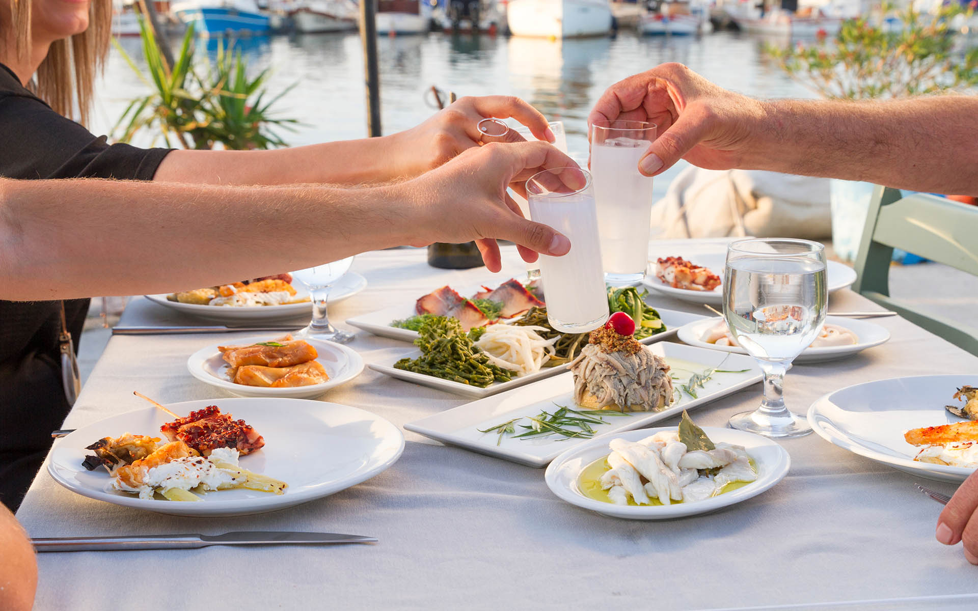 Lovely Couple or Friends Sitting, Drinking, Say Cheers and drinking Turkish Traditional Drink Raki. Ouzo is a dry anise flavoured aperitif that is widely consumed in Greece, Turkey, Cyprus and Lebanon