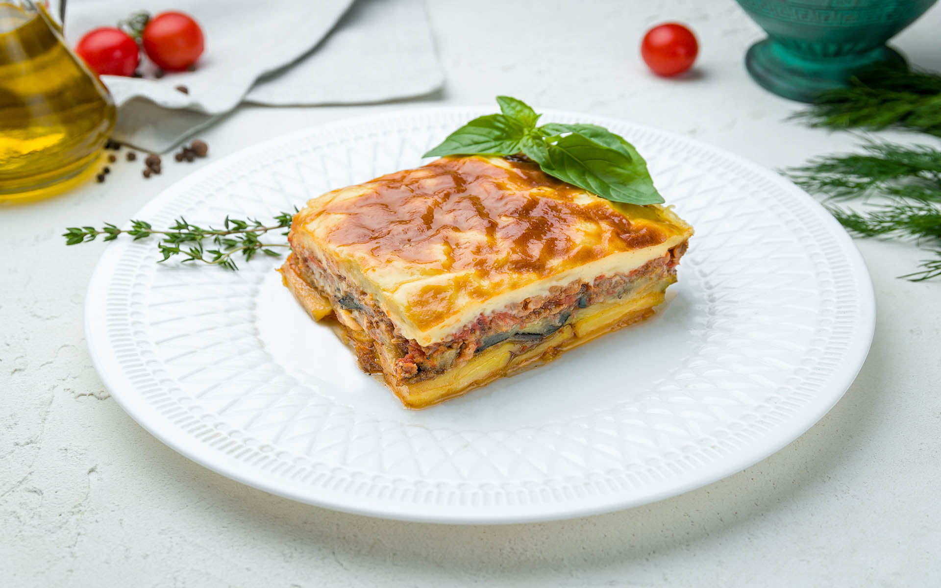 Eggplant moussaka Greek cuisine on white plate on white concrete table