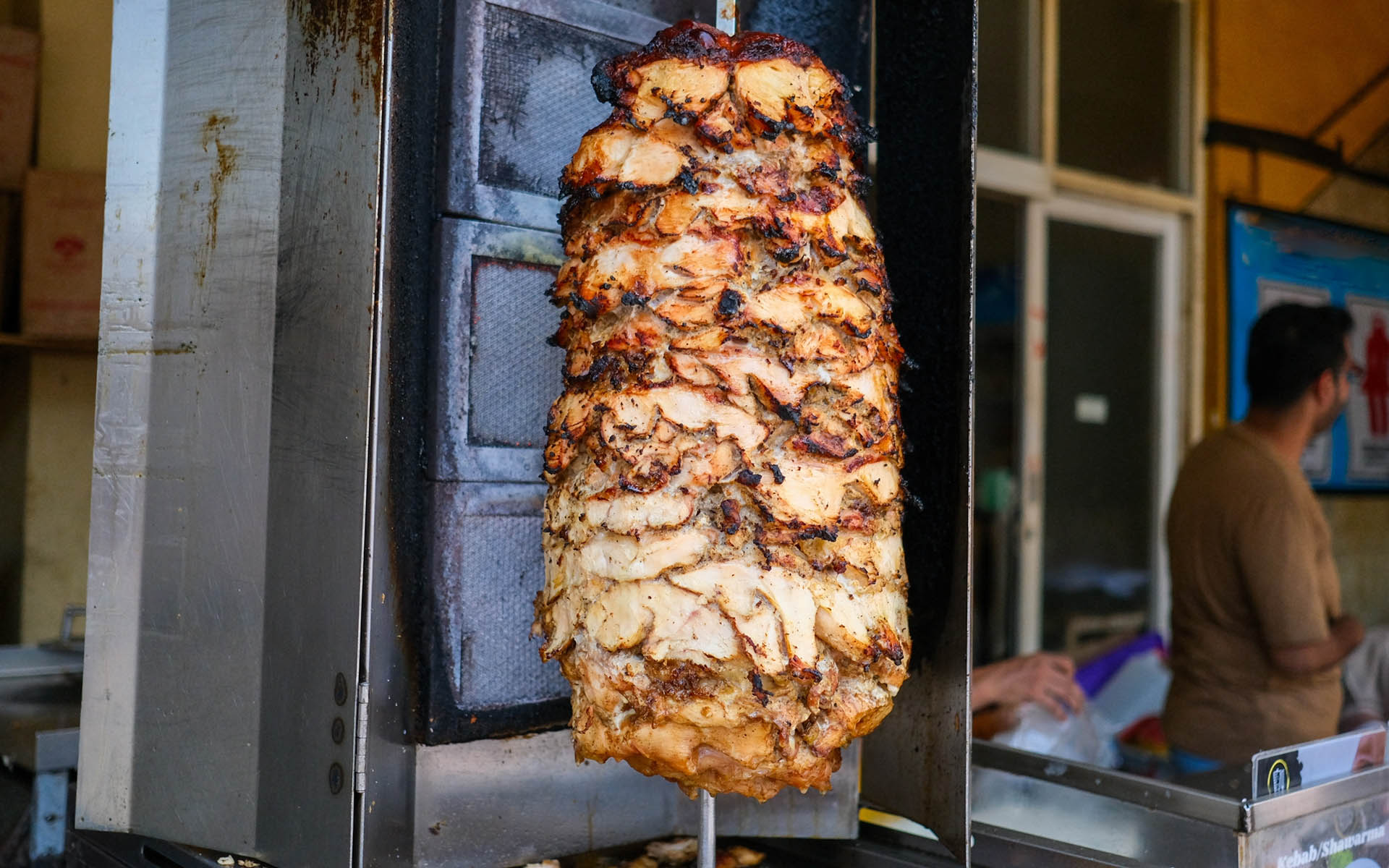 Arab Shawarma of meat chicken preparation placed on spit grilled with burn.