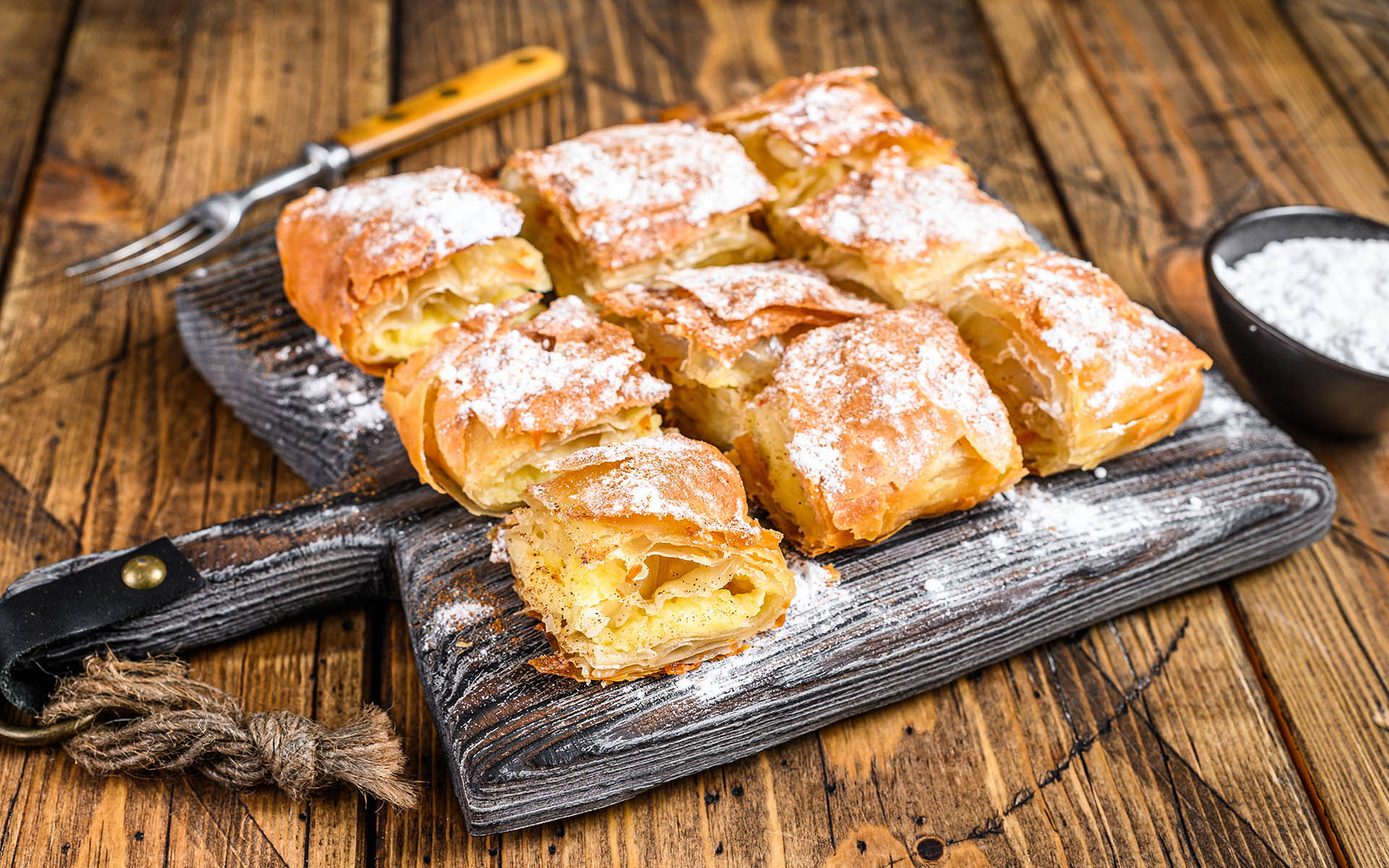 Greek pastry Bougatsa with phyllo dough and semolina custard cream. Wooden background. Top view.